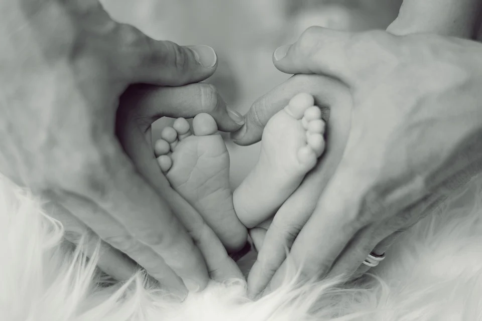 photos de mains de parents tenant les pieds de leurr bébé formant un coeur